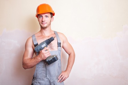 A man in overalls and helmet with a screwdriverの写真素材