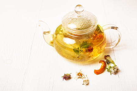 Glass teapot with herbal tea on a white tableの写真素材