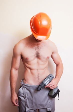 A man with a naked torso holding a screwdriverの写真素材