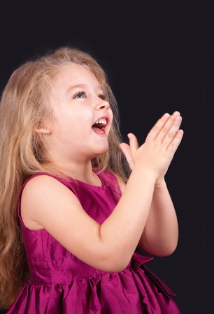 Little cute girl in a pink dress on a black background in the studioの写真素材