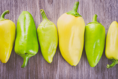 Several green and yellow peppers in a row on the tableの写真素材