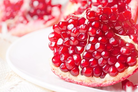 Closeup sliced pomegranate on a white plateの写真素材