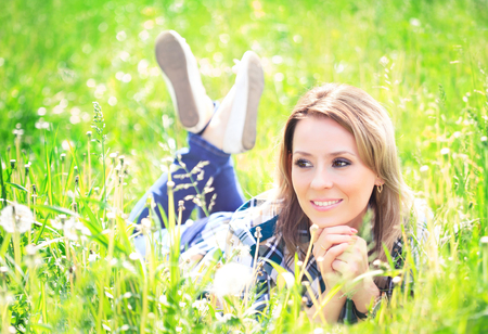Portrait of a beautiful young woman lying in the grass sunny summer dayの写真素材
