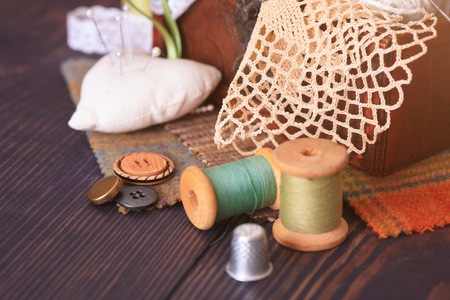 Spool of thread, a thimble and a box with needlework on a wooden table close-upの写真素材