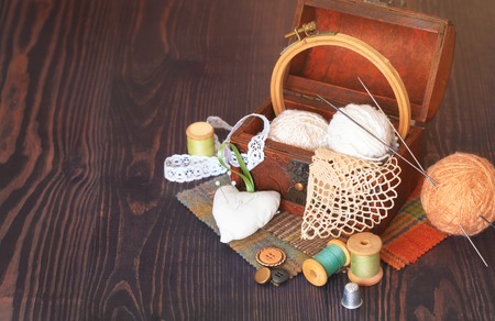 Spool of thread, a thimble and a box with needlework on a wooden table close-upの写真素材
