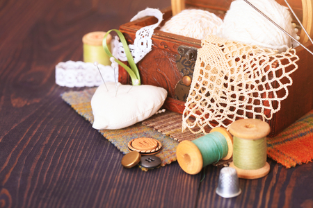 Spool of thread, a thimble and a box with needlework on a wooden table close-upの写真素材