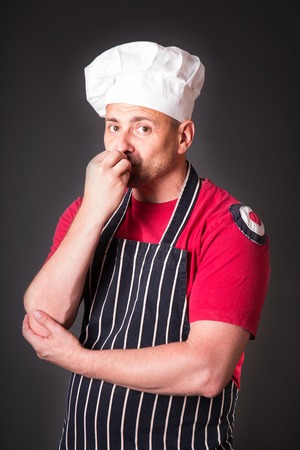Portrait of a cook man doing a success symbol in the studio on a black backgroundの写真素材