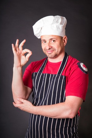Portrait of cook with gesture okay in the studio on a black backgroundの写真素材
