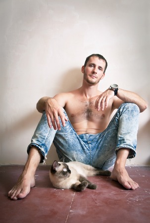 Young man is sitting on the floor with his catの写真素材
