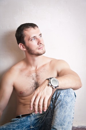 Portrait of young attractive man sitting on the floor near the wallの写真素材