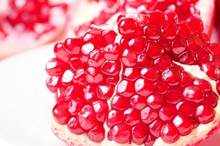 Piece of juicy ripe pomegranate on a white plate closeupの写真素材