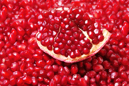 Red fresh piece of pomegranate closeup on a background grainsの写真素材
