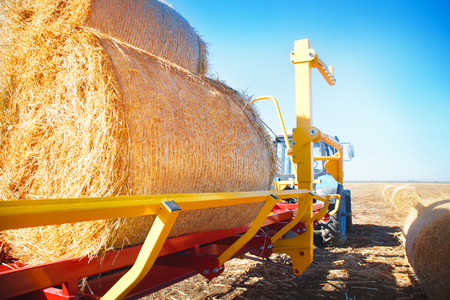 Straw on a trailer from a tractor in a field on a sunny dayの写真素材
