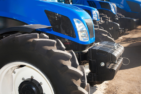 Close up of blue modern tractors on a rowの写真素材