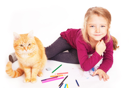 Little cute girl with colored pencils and red cat lying on the floor on a white backgroundの写真素材