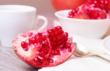 Piece of juicy ripe pomegranate on a white plate closeupの写真素材