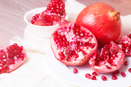 Piece of juicy ripe pomegranate on a white plate closeupの写真素材