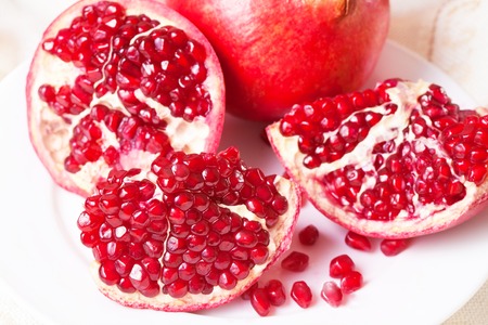 Closeup sliced pomegranate on a white plateの写真素材