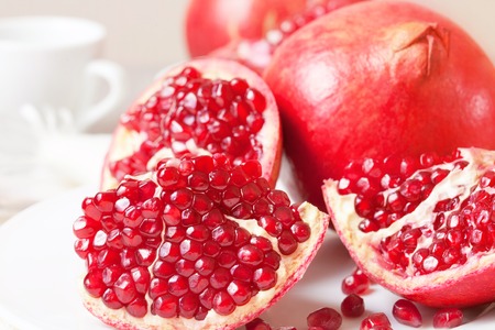 Piece of juicy ripe pomegranate on a white plate closeupの写真素材