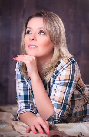 Portrait of a young attractive woman lying on a plaid blanket, close-up portrait, studio shootingの写真素材