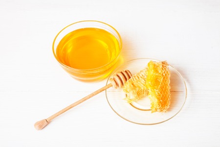 Honey with a wooden spoon on a white tableの写真素材