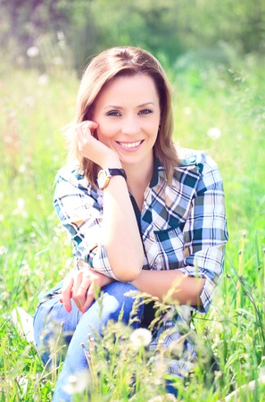 Portrait of a beautiful attractive woman in the grass on the natureの写真素材