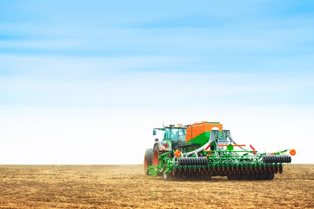 Tractor with a harrow to work the land fieldの写真素材