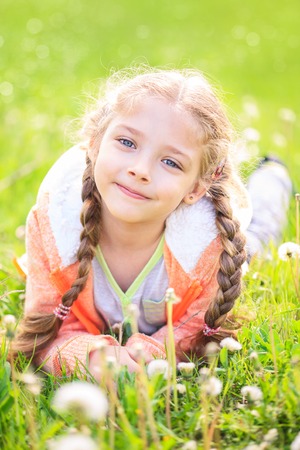 Cute little girl on the meadow in bright summer dayの写真素材