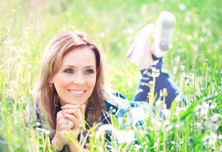 Portrait of a beautiful young woman lying in the grass sunny summer dayの写真素材