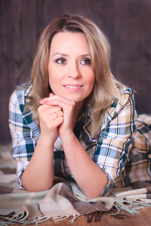 Portrait of a young attractive woman lying on a plaid blanket, close-up portrait, studio shootingの写真素材