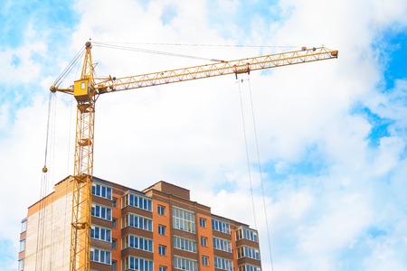 Construction crane and apartment building against the blue sky.の写真素材