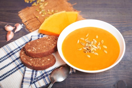 Pumpkin soup with seeds on a wooden tableの写真素材