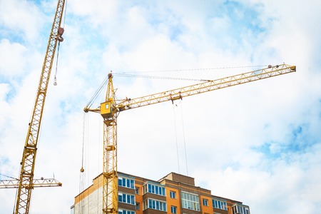 Construction crane and apartment building against the blue sky.の写真素材