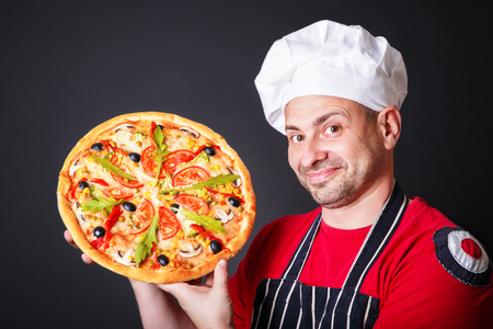 Portrait of happy attractive cook with a pizza in his handsの写真素材