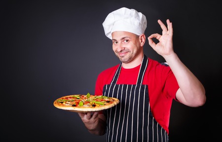 Portrait of happy attractive cook with a pizza in his handsの写真素材