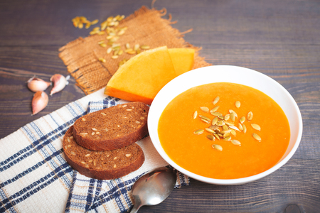 Pumpkin soup with seeds on a wooden tableの写真素材