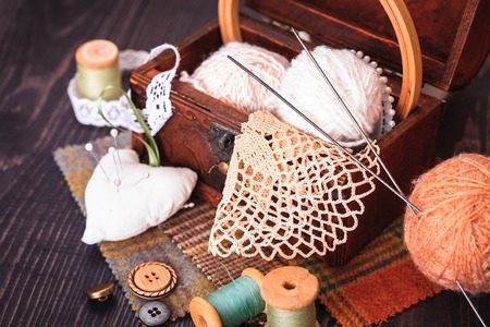 Spool of thread, a thimble and a box with needlework on a wooden table close-upの写真素材