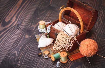 Spool of thread, a thimble and a box with needlework on a wooden table close-upの写真素材