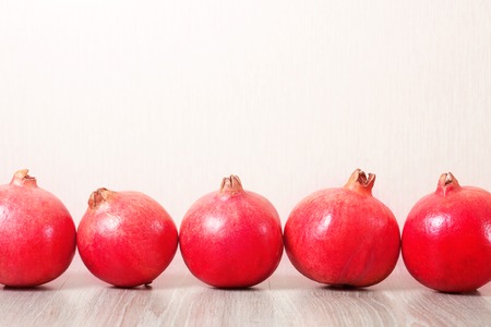 Several ripe pomegranates in a row on the tableの写真素材