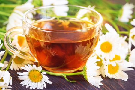 Chamomile tea in a transparent cup on a wooden table. The concept of herbal medicine.の写真素材