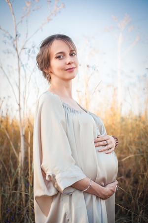 Portrait of a pregnant woman in the sunset light on the nature of the fieldの写真素材