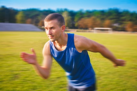 Young handsome sportsman running outdoors. Fit sporty man is at outdoor stadium.の写真素材