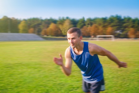 Young handsome sportsman running outdoors. Fit sporty man is at outdoor stadium.の写真素材