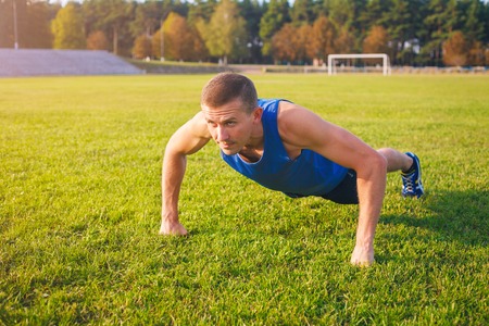 Fitness man doing push-ups on the grass. Sports and active lifestyle.の写真素材