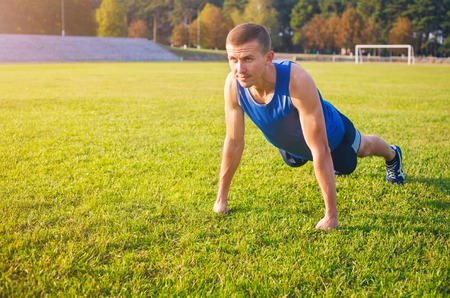 Fitness man doing push-ups on the grass. Sports and active lifestyle.の写真素材