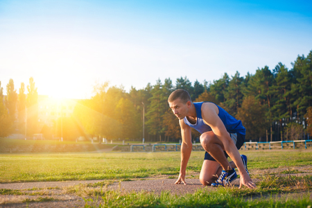 Man in low start position on old stadium. Athlete in starting position. Running, jogging, cardio, sport, active lifestyle concept.の写真素材