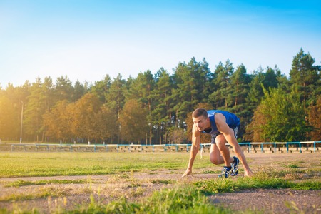 Man in low start position on old stadium. Athlete in starting position. Running, jogging, cardio, sport, active lifestyle concept.の写真素材