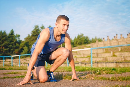 Man in low start position on old stadium. Athlete in starting position. Running, jogging, cardio, sport, active lifestyle concept.の写真素材