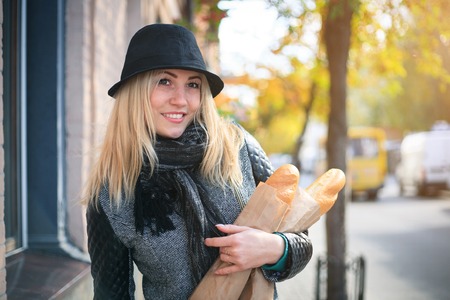 Young beautiful woman with a loaf of bread in her hands in autumn. Outdoors portrait.の写真素材