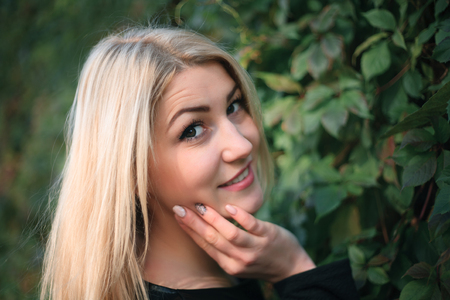 Portrait of an attractive young woman on a background of green ivy leavesの写真素材